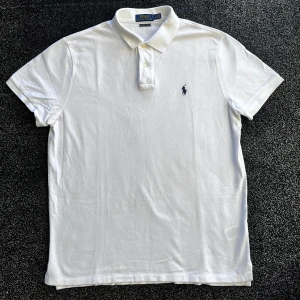 Ralph Lauren pike - Säljer en klassisk vit pikétröja från Polo Ralph Lauren med korta ärmar och krage med två knappar. Tröjan har den ikoniska broderade loggan på bröstet och är gjord i mjuk bomull. Perfekt för dig som gillar stilrena och tidlösa plagg. Storlek L, skick 9/10, pris går att diskutera✅