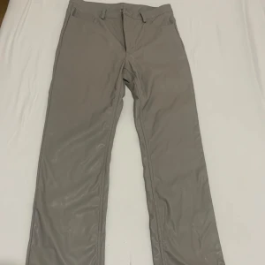 Gråa skinnbyxor från Weekday - Snygga gråa skinnbyxor från Weekday med raka ben och klassisk femficksmodell. Byxorna har bälteshällor, dragkedja och knapp framtill. Materialet är syntetiskt skinn som ger en cool och modern look.