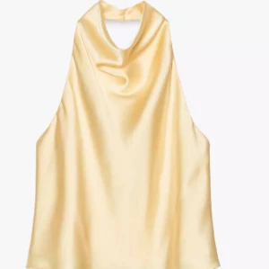 Gul halterneck topp  - Snygg topp i  gul satin med halterneck och lätt draperad framsida. Perfekt för dig som gillar en stilren och trendig look med lyxig känsla. Toppen är ärmlös och har en mjuk glansig finish. Aldrig använd!