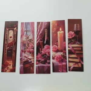 Romantiska bokmärken (set om 5) - Fem vackra bokmärken med romantiska motiv: rosor, böcker, vin, ljus och choklad. Perfekta för dig som älskar att läsa och vill ha en mysig känsla i varje bok. Passar utmärkt som present till bokälskare eller för att göra din egen läsupplevelse extra speciell.