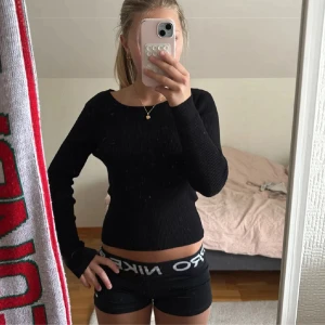 Svart ribbad tröja med öppen rygg från Zara - Svart långärmad ribbad tröja från Zara med snygg öppen rygg och knytband upptill. Tröjan är croppad och har en tight passform som framhäver midjan. 