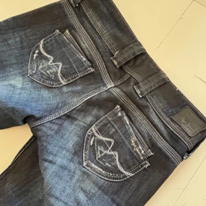 Mörkblå lågmidjade Pepe Jeans - Snygga mörkblå jeans från Pepe Jeans med superlåg midja och raka ben. Jeansen har dubbla knappar i midjan och bakfickor med broderad detalj. Jag är 171 cm för referens
