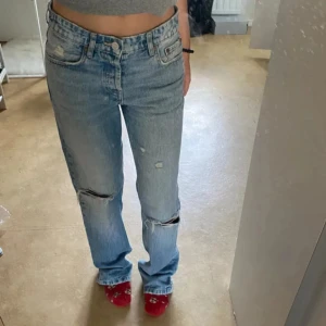 Ljusblå slitna jeans med raka ben - Storlek 36 Säljer ett par ljusblå jeans med raka ben och slitningar vid knäna. Jeansen har klassisk femficksdesign, normal passform och är högmidjade. Perfekta för en avslappnad och trendig look.