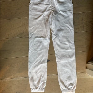 Vita mjukisbyxor  - Säljer ett par vita mjukisbyxor med resår i bensluten och sidofickor. Byxorna har en avslappnad passform och är perfekta för chill dagar. Tillverkade i mjukt bomullsmaterial för extra komfort.