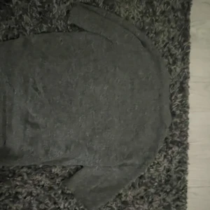 Mörkgrå stickad tröja från H&M - Säljer en mörkgrå stickad tröja från H&M i storlek S. Tröjan har rund hals och långa ärmar, perfekt för dig som gillar enkel och chill stil. Materialet är mjukt och ger en skön känsla, passar nice till jeans eller kjol.