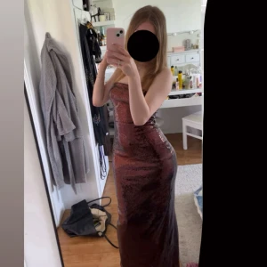 Röd brun (rost) glittrig axelbandslös långklänning  - Säljer en fin glittrig långklänning med paljetter. Klänningen är axelbandslös (tubklänning) och har en tight passform som framhäver figuren. Jätte bra kvalitet, Perfekt för balen eller annat festande! Använd en gång bara och inga defekter, pris kan diskuteras 💕💕