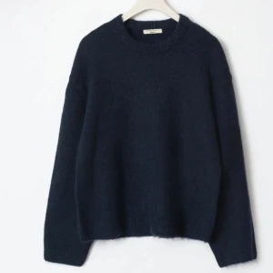 Mörkblå stickad tröja från Gina tricot - Säljer en mörkblå stickad tröja med rund hals och långa ärmar. Tröjan har en loose passform och är tillverkad i mjuk ull som håller dig varm under kyliga dagar. Perfekt att slänga på sig när du vill vara både chill och snygg.