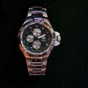 Adidas silverfärgad kronografklocka - Snygg och sportig kronografklocka från Adidas i silverfärgat rostfritt stål. Adidas-loggan syns tydligt på både urtavlan och spännet. Perfekt för dig som gillar stilren design. Pris kan diskuteras vid snabba affär 