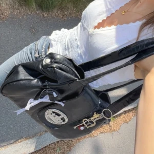 Svart axelväska med krona och rosett - Cool svart axelväska från Bris & Co i skinnimitation med blingad krona framtill, vit rosett och flera nyckelringar. Väskan har långa handtag och gott om plats för allt du behöver. Perfekt för dig som gillar detaljer och vill sticka ut. ‼️har tejpat handtaget, syns på första bilden‼️ fin och rymlig💗(inte från guess utan Friis o company)  kom privat vid frågor