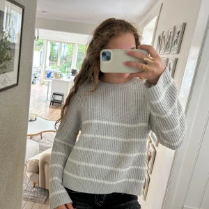 Ljusgrå stickad randig tröja - Supermysig stickad tröja med vita ränder. ”Delad” nere på sidorna. 💖 storlek 152 men är ganska stor i storleken så skulle passa bra på längre också.