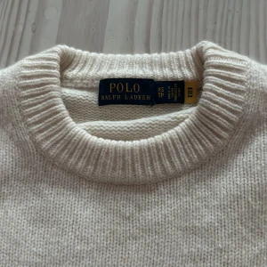 Beige stickad tröja från Polo Ralph Lauren - Säljer en stilren beige stickad tröja från Polo Ralph Lauren i storlek XS. Tröjan har rund halsringning, ribbade muddar och ärmar med snygg struktur. Perfekt för dig som gillar klassisk och enkel stil med en touch av lyx.