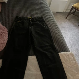 Svarta butter jeans med broderad bakficka - Säljer ett par svarta raka jeans från Butter med coolt broderi på bakfickan. Jeansen har klassisk femficksdesign och orange sömmar. Sönder längst ner vid fötterna. (Kolla bilderna)