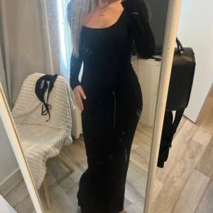 Svart långärmad långklänning - Supersnygg svart långklänning med lång ärm och figurnära passform. Klänningen har en stilren, rundad urringning och är perfekt för dig som gillar en enkel men elegant look. Materialet är stretchigt och följsamt, vilket gör den bekväm att bära hela dagen. Storlek xs och från Nelly. Till alla långa tjejer!!