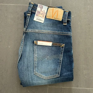 Nudie jeans  - Nudie Jeans av modellen Thinn Finn Storlek: 30/34 - Skicket på jeansen är ny med prislapp - 100/10 - mitt pris: 599- Nypris: 1599kr.   En stor fördel med Nudies jeans jämfört mot Levis, Tiger of Sweden, Replay, Lee, Acne, dondup osv. Ar att du kan lämna in dem gratis for reparation eller uppläggning i Stockholm, Göteborg eller Malmö. Pa sa vis förlängs livslängden rejalt.