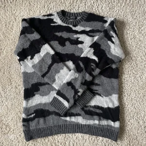 Grå och svart camouflagemönstrad tröja från MAN - Säljer en cool grå och svart camouflagemönstrad tröja från MAN. Tröjan har långa ärmar och en rund halsringning med ribbade kanter. Perfekt för en avslappnad stil. Hör av dig vid intresse! tröjan är small men den är väldigt oversized 