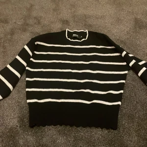 Svart och vit randig tröja från ONLY - Säljer en snygg svart tröja med vita ränder från ONLY. Tröjan har långa ärmar och en ribbad struktur med en stilren design. Perfekt för en avslappnad look. Hör av dig vid intresse!