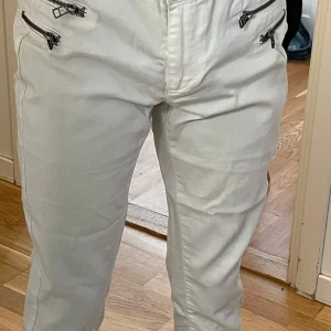 Vita byxor med dragkedjor från Only - Snygga vita byxor från Only med coola dragkedjedetaljer framtill. Byxorna har en modern design och är perfekta för en stilren look. De har en normal passform och är tillverkade i ett bekvämt material.