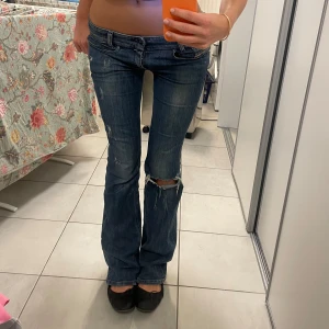 Lågmidjade bootcut jeans från Diesel  - Säljer ett par blå jeans från Diesel med slitningar på knäna. De har en bootcut-stil och är lågmidjade. Perfekta nu till våren! Lite slitna nertill men absolut inte mycket 