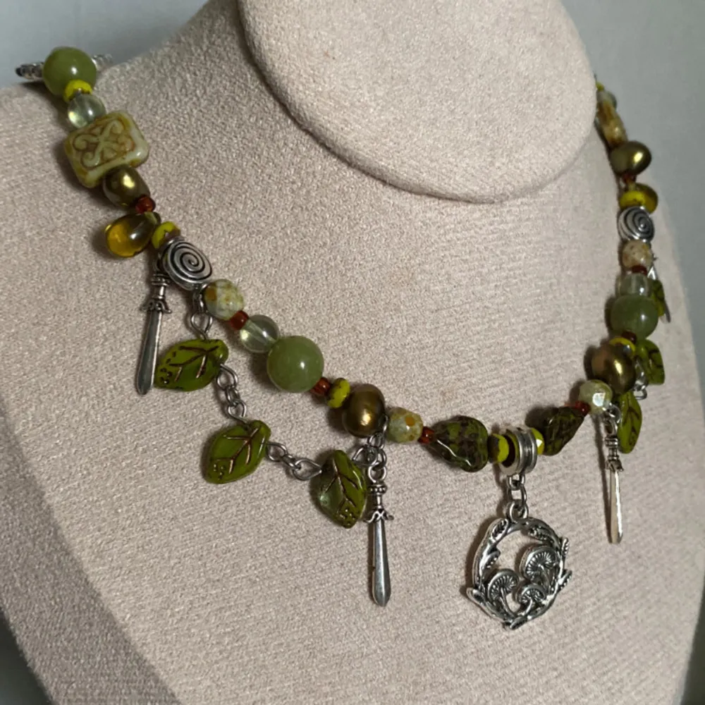 Unikt halsband med jade, tjeckiska glaspÀrlor och sötvattenspÀrlor. Detaljer som fjÀrilar, blad och svampberlocker. VÀldigt goblincore, vÀldigt svamp-y :). Asusteet.