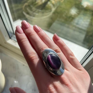 Stilren silverring med lila sten - Säljer en elegant silverring med en stor oval lila sten i mitten. Den är i mycket bra skick och går att spänna ut och in💜