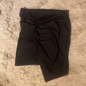 Svart kjol från Gina Tricot - Snygg svart kjol från Gina Tricot i en mjuk polyesterblandning. Kjolen har en elegant drapering framtill och en bekväm passform. Perfekt för en stilren look.