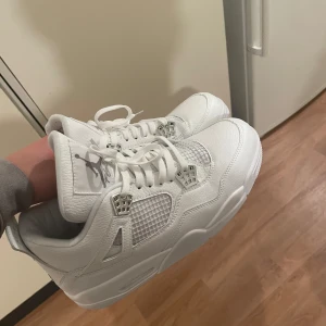 Jorden 4 Nike metallic silver - Säljer ett par stilrena vita sneakers från Nike med klassisk design. Skorna har snörning och en ikonisk logga på hälen. Perfekta för en sportig look.