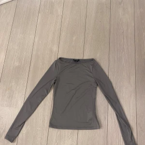 Grå långärmad topp från Monki - Säljer en stilren grå långärmad topp från monki. Toppen har en enkel design med en rund halsringning.