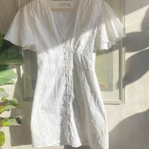 Vit klänning med broderade detaljer - Säljer min älskade studentklänning som förtjänar en ny ägare! Den har broderade detaljer och v-ringning och är även insydd i midjan. Den har volangärmar och knappar framtill. Perfekt för sommarens alla tillfällen!💓