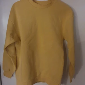 Gul sweatshirt - Säljer en gul sweatshirt med rund hals och långa ärmar. Tröjan har en avslappnad passform.