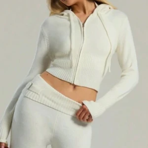 Vitt stitckat mjukisset - Snyggt vitt stickat set med mjukisbyxor med låg midja och ribbade detaljer. Med en hoodie till med ribbade detaljer på också! Perfekta för en avslappnad stil med en skön passform. 