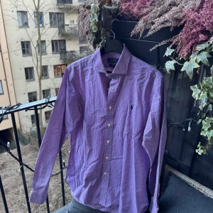 Lila rutig skjorta från  Ralph Lauren - Mycket fin skjorta inför vardagen eller jobbet/skolan 🤩  •Skick: 9.5/10 finns få tecken på användning   •storlek📏: L enligt mått   •Nypris/Butikspris:💰 ~1599kr   Köp gärna i bundles för att underlätta i frakt och på detta vis blir jag mer flexibel i pris! Våga buda! 🚚🤝