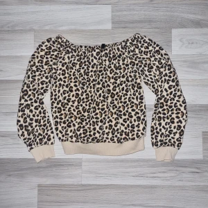 Leopardmönstrad offshoulder-tröja från H&M  - Säljer en snygg leopardmönstrad offshoulder-tröja från Divided,  H&M. Tröjan har långa ärmar och en bekväm passform med elastiska muddar vid ärmslut och nederkant. Perfekt för att ge din outfit en trendig touch 🐆