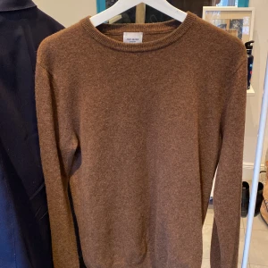 Brun kashmirtröja från John Henric 100% Kashmir  - Säljer en lyxig brun kashmirtröja från John Henric i storlek m. Tröjan har en klassisk rund hals och långa ärmar, perfekt för kyliga dagar. Den är tillverkad i 100% kashmir vilket ger en mjuk och bekväm känsla. Passar till de mesta 