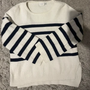Vit och marinblå randig tröja från Vila - Snygg vit tröja med marinblå ränder från Vila. Tröjan är långärmad och ribbad, vilket ger en skön känsla. Stl M men skulle mer säga att den är som S.