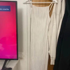 Vit långklänning från Shein - Säljer en elegant vit långklänning från Shein. Klänningen har smala axelband och ett subtilt ribbat mönster som ger en stilren look. Perfekt för sommarens alla tillfällen.