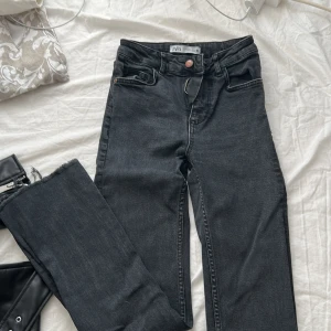 Svarta jeans från Zara - Snygga svarta jeans från Zara med hög midja och dragkedja. Perfekta för en stilren look. De har en klassisk design med fem fickor och knappstängning.