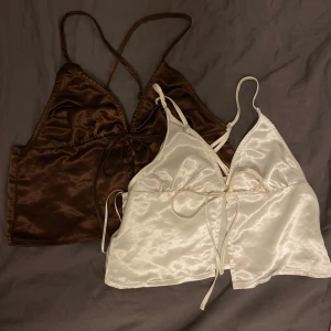 Brun och vit satinlinnetopp från H&M Divided - Två eleganta satinlinnetoppar från H&M Divided i brunt och vitt. Båda topparna har smala axelband och knytning framtill för en justerbar passform. Perfekta för sommaren😎.  Passform xs lite mer som xxs men helt oanvända. 120kr för båda tillsammans.