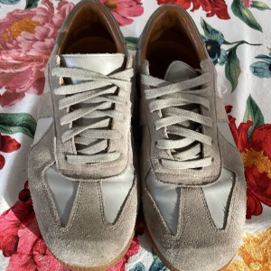 Maison margiela - Snygga beige sneakers med mockadetaljer och snörning. Skorna har en stilren design med en kombination av mocka och syntetmaterial. Perfekta för en avslappnad stil.