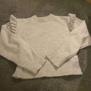 Grå stickad tröja med volangdetaljer - Säljer en grå stickad tröja med volangdetaljer på axlarna. Tröjan är från Gina tricot och är i bra skick. Den är i storlek 158/164. Pris kan diskuteras privat💞