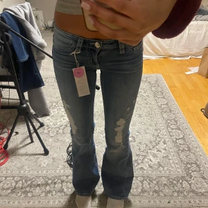 Blå utsvängda jeans med slitniningar, ginatricot - Snygga blå bootcut jeans i TALL från gina med slitningar på framsidan. Helt slutsålda i storlek xs. Om de ska säljas vill jag ha ett bra pris för de så jag kan köpa i storlek S då dessa är lite för små för mig tyvärr. Jag är 175 för referens. Mina nya favorit jeans Från Gina Young 14+