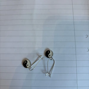 Yin och Yang örhängen - Säljer ett par unika örhängen med Yin och Yang-motiv. De har en svart och vit design och är perfekta för att ge en stilfull touch till din outfit.