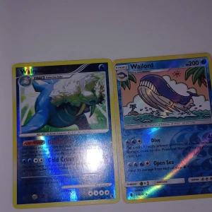 Pokémonkort Wailord och Wailrein - Två holografiska Pokémonkort: Wailrein och Wailord. Båda korten har blå och silvrig design med glansig yta. Wailrein visar en isblå Pokémon med vita detaljer och Wailord ett stort blått val-liknande monster i vattenmiljö. Perfekt för samlare eller Pokémonfans.