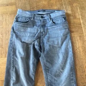 Grå jeansbyxor från Replay - Snygga grå jeansbyxor från Replay med klassisk femficksdesign och raka ben. Byxorna har diskreta sömmar och logotyp på bakfickan. Perfekta för dig som gillar stilrena och enkla jeans.
