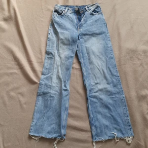 Blåa Jeans monki  - Blåa lätt vida jeans från Monki med råa benslut. Storlek 24.