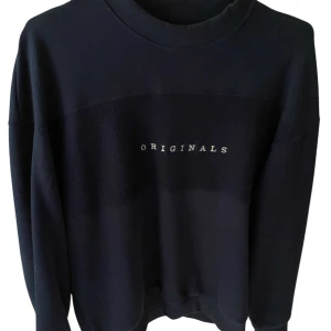 Svart sweatshirt från Jack & Jones Originals - En mörkblå sweatshirt från Jack & Jones Originals med tryckt text på bröstet. Tröjan har rund halsringning och långa ärmar. Perfekt för en avslappnad stil.