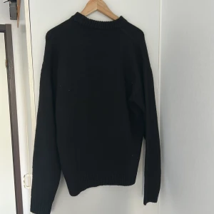 Svart stickad tröja från Jack & Jones - En klassisk svart stickad tröja från Jack & Jones. Tröjan har rund halsringning och långa ärmar med ribbade muddar vid ärmslut och nederkant. Perfekt för lager-på-lager och enkel att matcha med olika outfits. Storleken är M men tröjan är stor och kan också passa någon som har storlek L