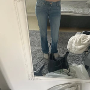Blå bootcut jeans - Säljer ett par klassiska blå bootcut jeans med normal passform. Jeansen har fem fickor, knapp och dragkedja framtill samt snygga sömmar. Perfekta för dig som gillar en tidlös stil med lite utsvängda ben.