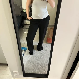 Svarta kostymbyxor med rak passform - Säljer ett par klassiska svarta kostymbyxor med rak passform och normal midja. Byxorna har diskreta fickor i sidorna och är perfekta för en stilren look. Materialet känns mjukt och följsamt, vilket gör dem bekväma att bära hela dagen.