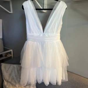 Vit tulle miniklänning med v-ringning - Studentklänning - 🌸Aldrig använd! Endast testad. 🌸Finns ett spänna så går att reglera hur djup v-ringning man vill ha (se bild 1 och 2) 🌼