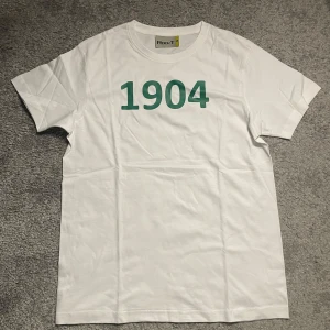 VSK t-shirt - Vit t-shirt från Rock T med grönt tryck '1904' på framsidan och 'Västra Aros' på baksidan. Alla storlekar finns. 50% går till tifo grupperna